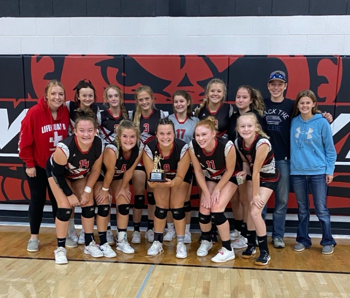 Two rows of Lamoni Volleyball team. Front middle teammate holding championship trophy.